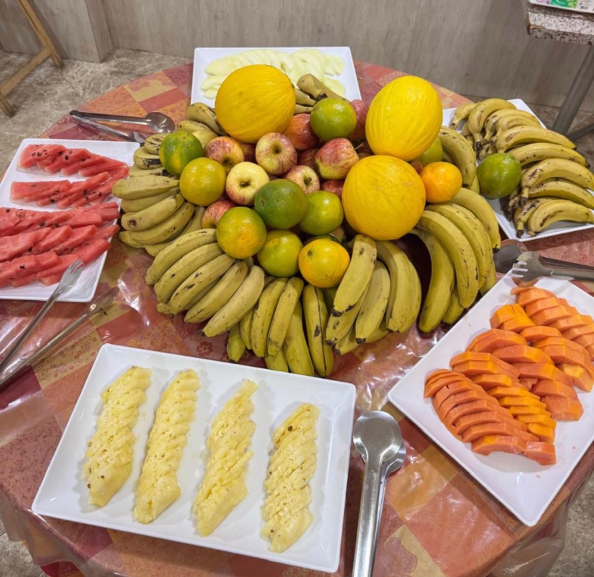 Mesa de frutas do café da manhã: melão, mamão, abacaxi, melancia e bananas